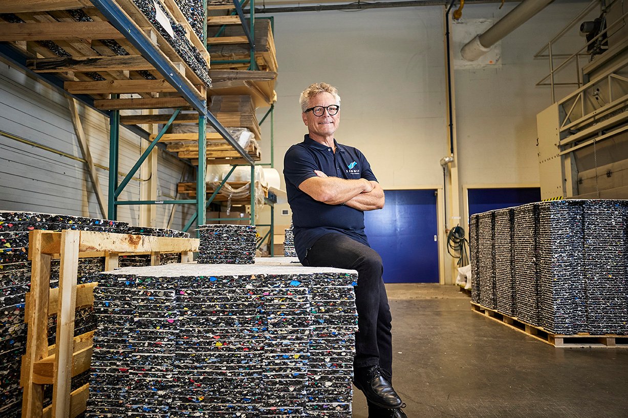Man next to a pile of shock pads in a warehouse